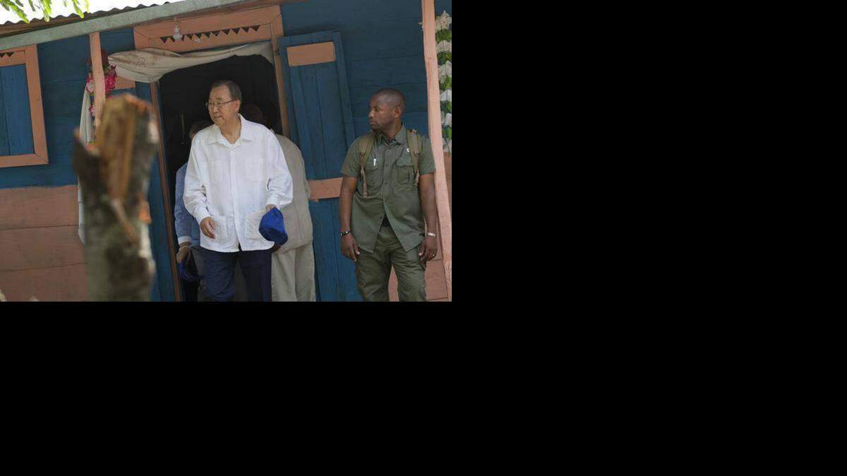 
U.N. Secretary General Ban Ki-moon emerges from a house in Haiti where he visited with family of cholera victims.
