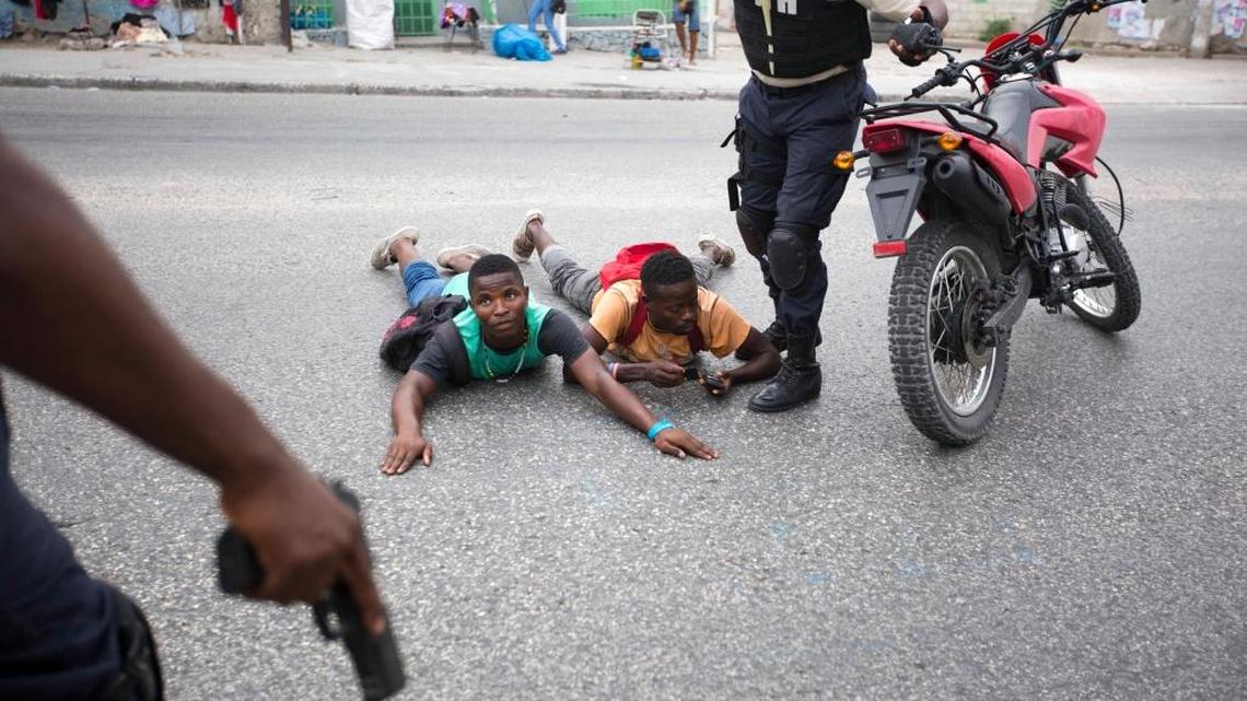 Two men are detained by national police officers during a protest against the official election results, in Port-au-Prince, Haiti, Thursday Nov. 26, 2015. The demonstrators are claiming fraud and are demanding that the Oct. 25 first-round presidential election where the top two finishers are government-backed candidate Jovenel Moise and former state construction chief Jude Celestin be annulled.