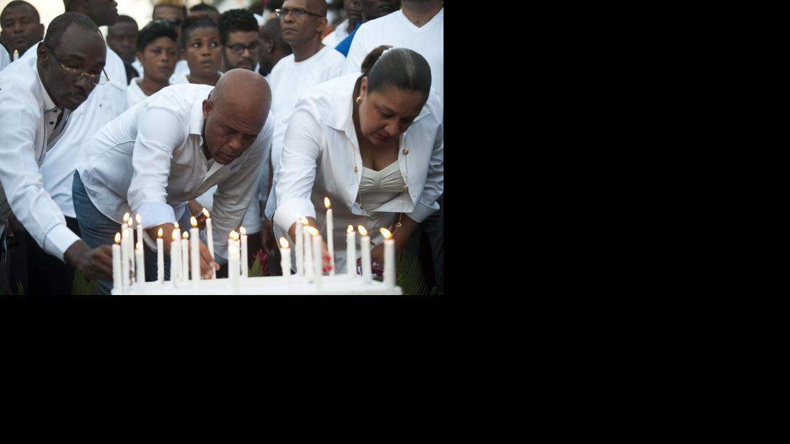 
Haitian President Michel Martelly, center, places a candle with First Lady Sophia Martelly, right, and Prime Minister of Haiti, Evans Paul, left, at the site of an accident during the march convened by the government in Port-au-Prince on February 17, 2015, in memory of the victims who died during celebrations in the National Carnival of Haiti. Haiti was plunged into mourning and Carnival festivities were cancelled after at least 16 people died when a high-voltage cable hit a parade float in the capital Port-au-Prince. 

