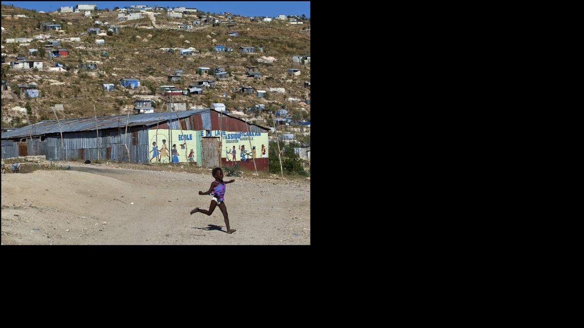 Claudia Saint-Elys, 5, runs near her family's market in Canaan, a neighborhood on the outskirts of Port-au-Prince that sprung up shortly after the 2010 earthquake on Thursday, Jan. 9, 2014.