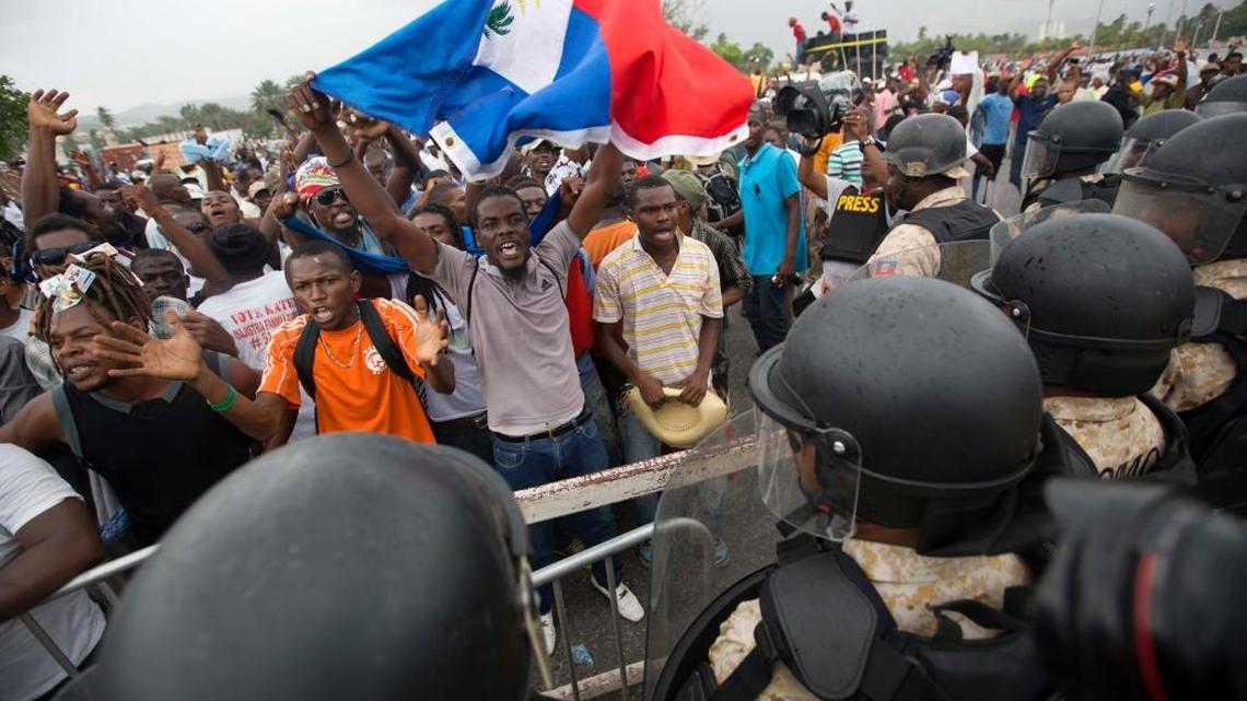 Supporters of presidential candidate Maryse Narcisse chant slogans against legislators in front of a police barricade near the entrance to the parliament building during a demonstration in support of interim President Jocelerme Privert, in Port-au-Prince, Haiti, Tuesday, June 21, 2016. The demonstrators are demanding the extension of the expired mandate of the interim president Privert.