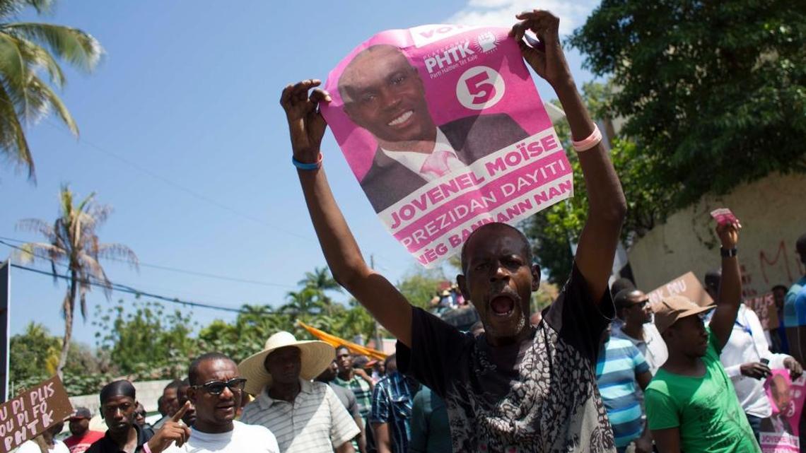 A supporter of presidential candidate Jovenel Moise, from the PHTK political party, holds up a picture of him during a protest demanding interim President Jocelerme Privert respect the upcoming election date in Port-au-Prince, Haiti, Wednesday, March 9, 2016. The next election is scheduled for April 24.