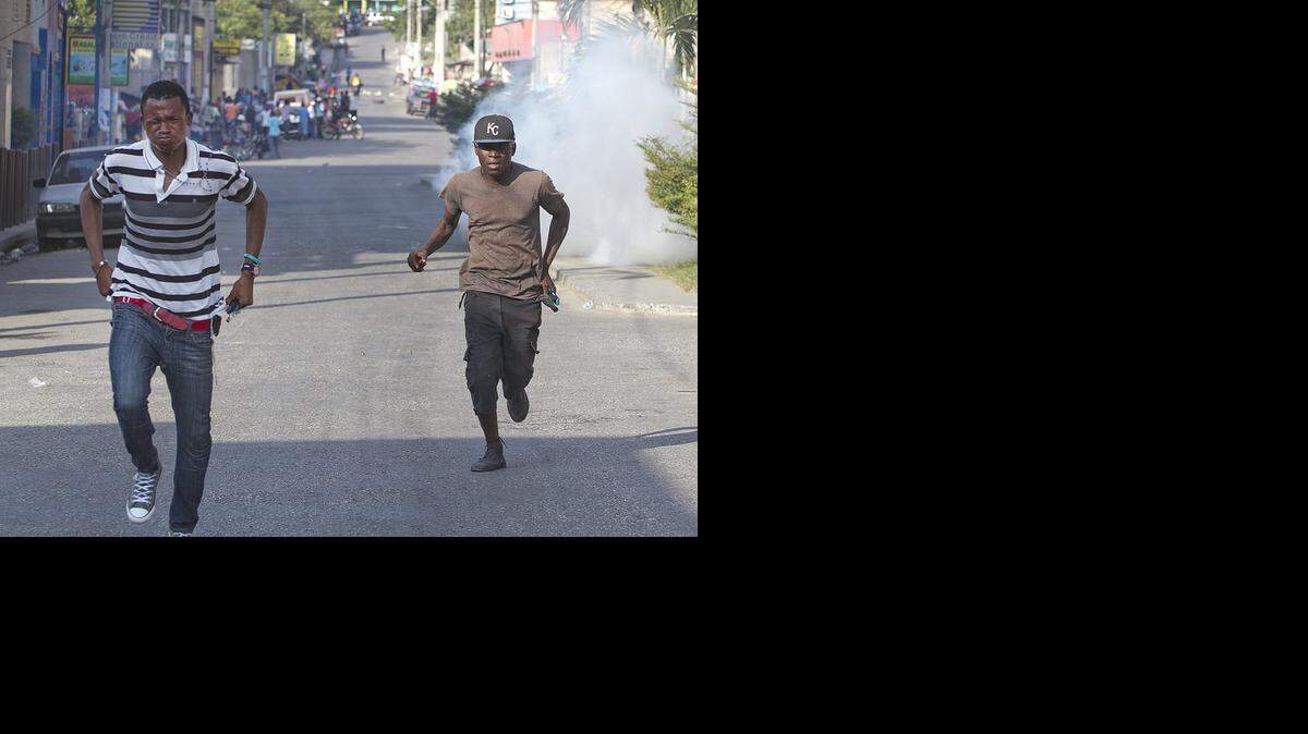 
Young men run from tear gas during an anti-government protest in downtown Port-au-Prince, Haiti on Saturday Dec. 13, 2014. As Haiti approaches the fifth anniversary of its devastating Jan. 12, 2010 earthquake, growing discontent among Haiti’s poor, black masses is fueling increasing demonstrations and calls for Pesident Michel Martelly to step down.
