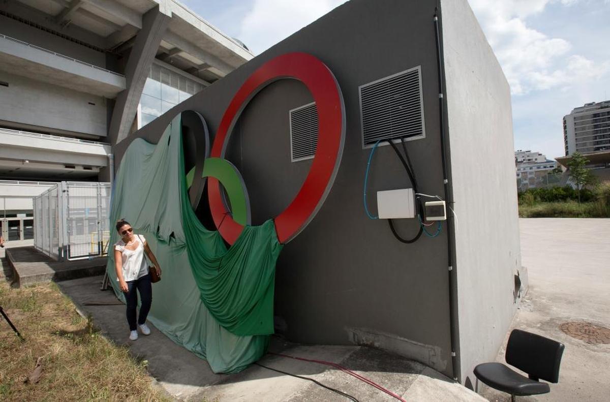 In this Feb. 2, 2017 photo, a woman walks past Olympic rings covered with a canvas at Maracana stadium in Rio de Janeiro. The stadium was renovated for the 2014 World Cup at a cost of about $500 million, and largely abandoned after the Olympics and Paralympics, then hit by vandals who ripped out thousands of seats and stole televisions.