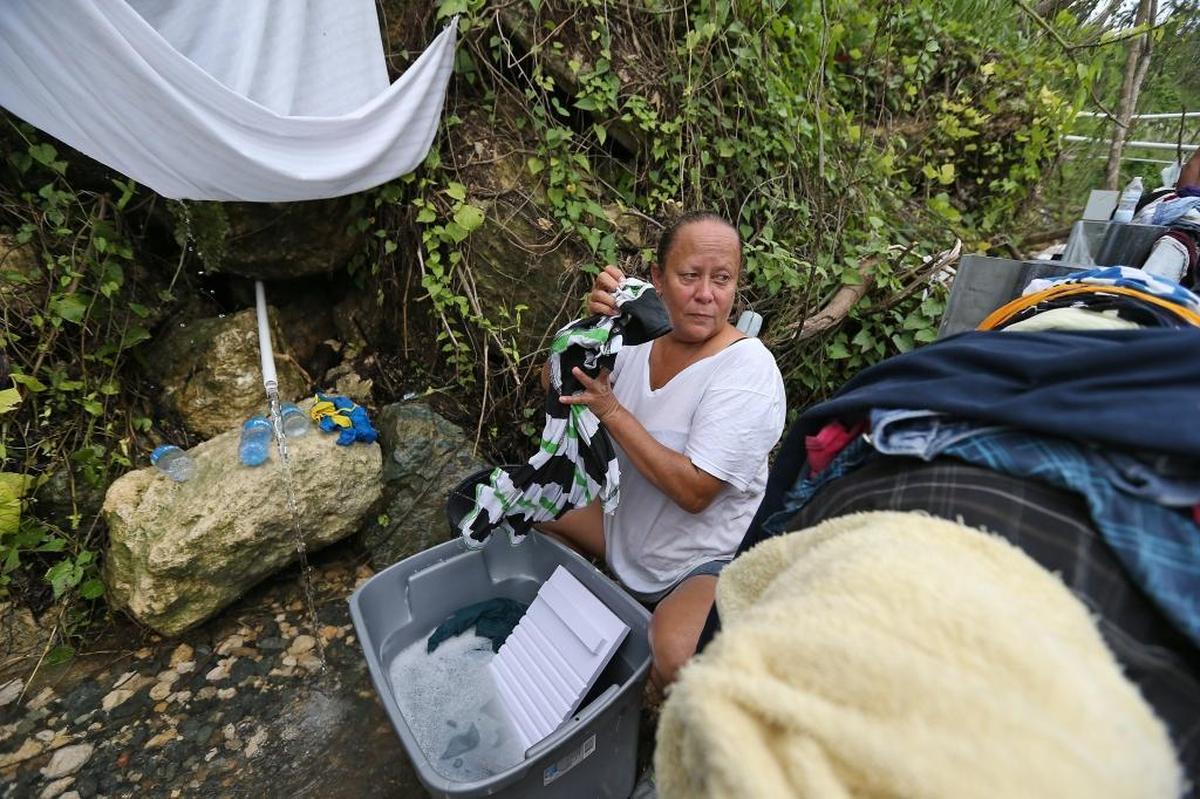 Utuado resident Maritza Collazo washes her clothes on the side of the highway in Utuado. Nearly six weeks after Hurricane Maria, she still had no running water in her home.