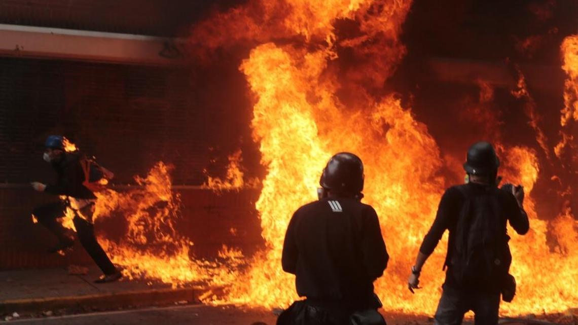 Anti-government protesters burn a Bolivarian National Guard motorbike, as one of them is covered in flames, left, during clashes with security forces blocking their march from reaching the National Assembly in Caracas, Venezuela, Wednesday, May 3, 2017. Driving the latest outrage is a decree by Venezuelan President Nicolas Maduro to begin the process of rewriting Venezuela's constitution.