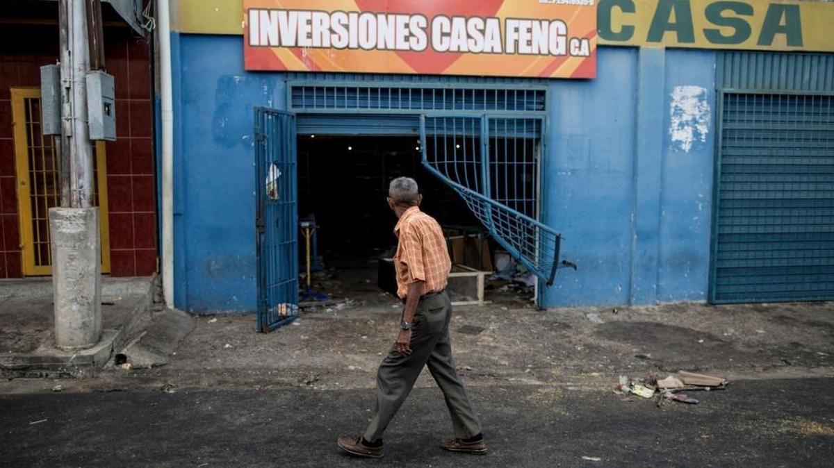 A man walks past a grocery store looted by demonstrators the night before in Ciudad Bolivar, Venezuela, Monday, Dec. 19, 2016. Last week, President Nicolas Maduro made an announcement annulling all 100-bolivar notes leading to massive lines at banks, and making cash transactions such as buying food or gasoline extremely difficult. Maduro suddenly changed course late Saturday, announcing the 100-bolivar notes could be used until Jan. 2. Before that announcement riots and looting broke out in several cities.