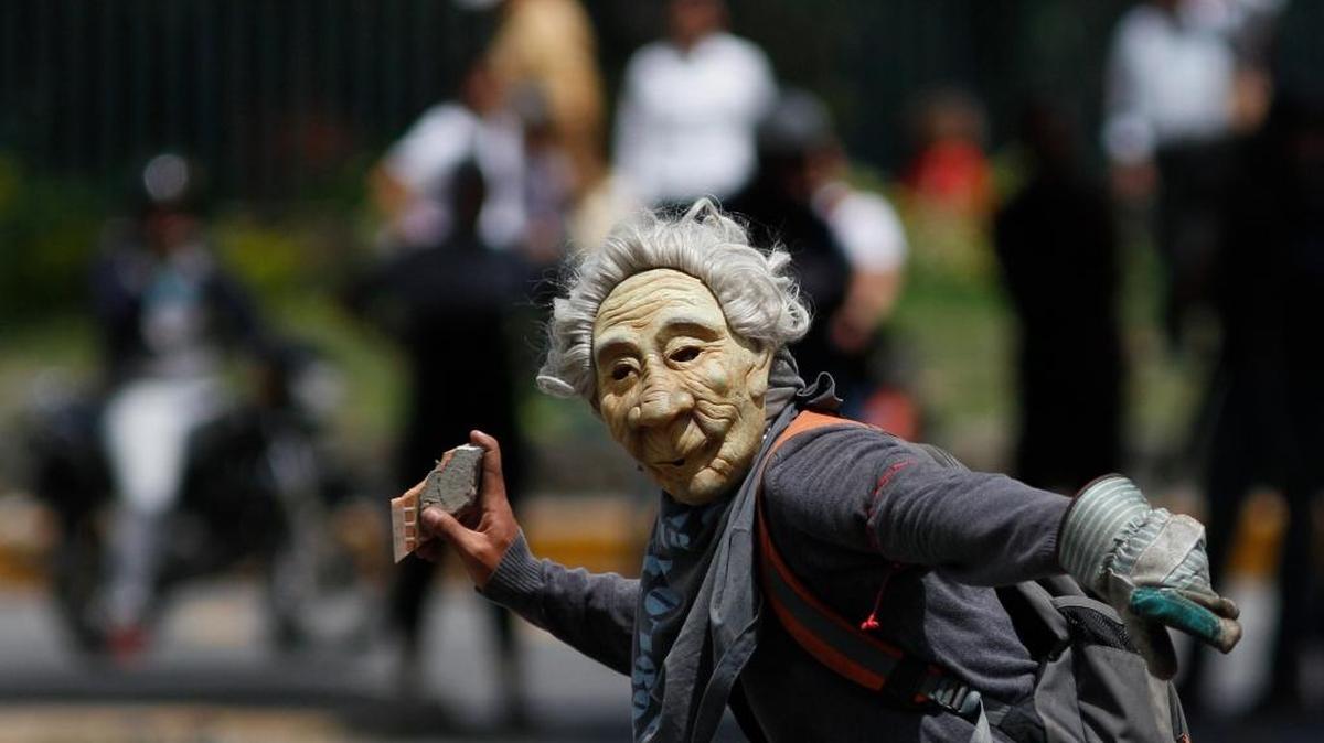 A masked anti-government protester aims an object at security forces during a call by the opposition to block roads for 10 hours in Caracas, Venezuela, Monday, July 10, 2017.