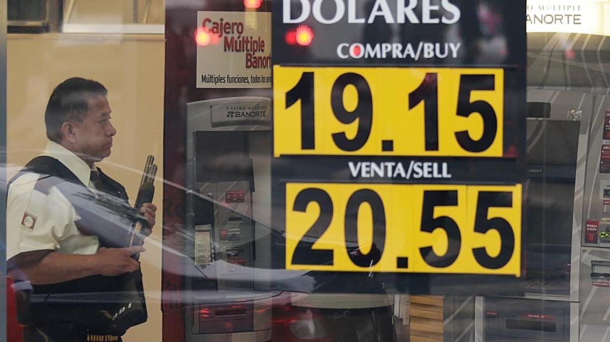 A guard stands inside a bank next to a sign displaying the rate exchange of the U.S. dollar, in Mexico City, Wednesday. The value of Mexico’s currency plunged sharply after the election of President-elect Donald Trump, who has denounced the North American Free Trade Agreement that has led to billions of dollars in trade between the two nations.