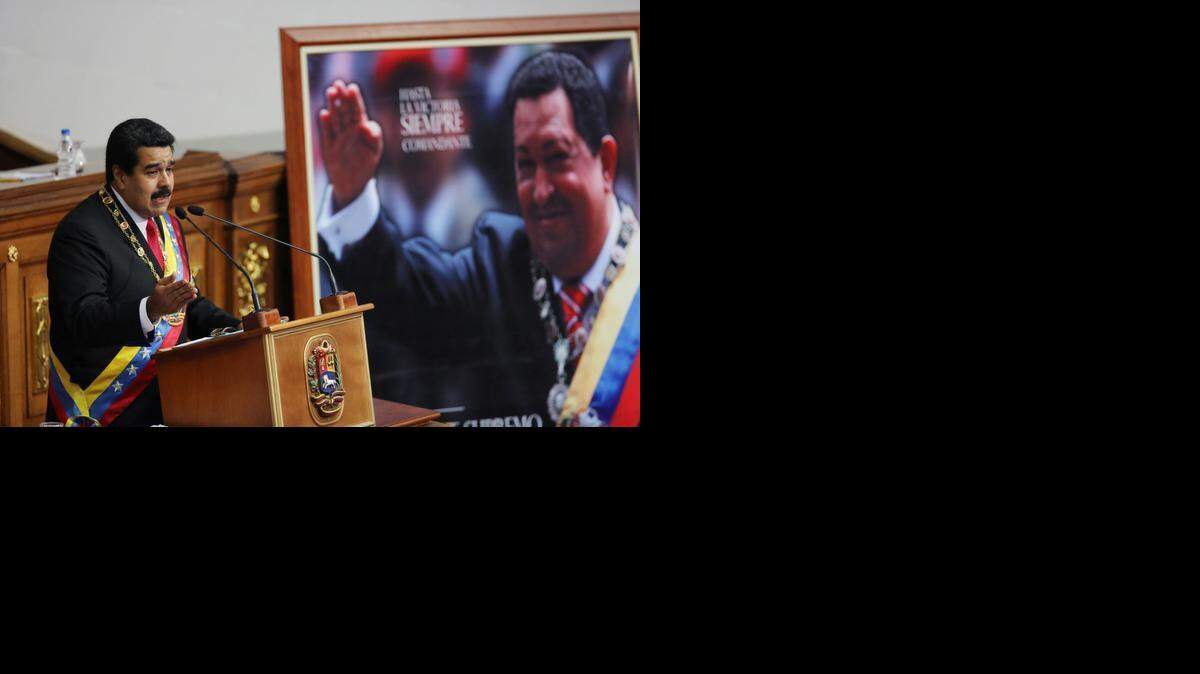 
BIG SPEECH: Venezuelan President Nicolas Maduro delivers his annual state-of-the-nation address Wednesday beside a framed poster featuring the late President Hugo Chavez at the National Assembly in Caracas.
