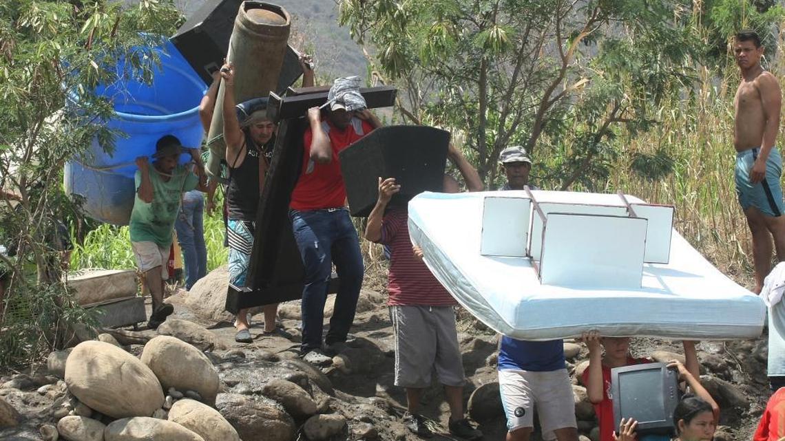 
Colombians line up on the bank of Tachira River, near San Antonio del Tachira, Venezuela, as they carry their belongings toward Colombia's community of La Parada, Tuesday, Aug. 25, 2015. Venezuelan President Nicolas Maduro vowed to extend a crackdown on illegal migrants from neighboring Colombia he blames for rampant crime and widespread shortages, while authorities across the border struggled to attend returning deportees. 
