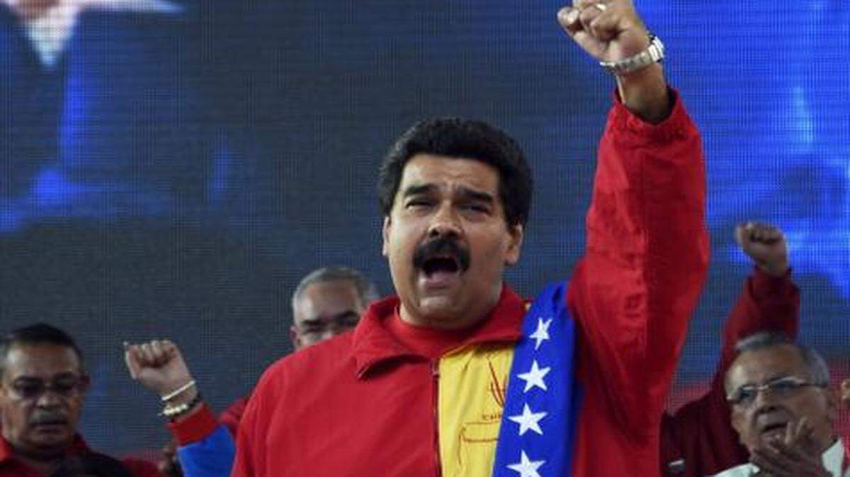 
Venezuelan President Nicolas Maduro gestures during the United Socialist Party of Venezuela's annual congress on July 31, 2014, at Caracas' Mountain Barracks, where the remains of Venezuelan former president Hugo Chavez (on screen) rest. 
