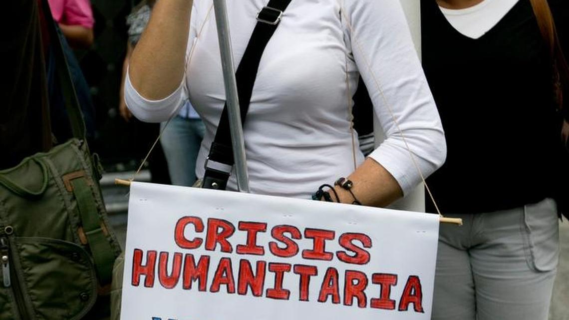 A woman chants while holding a sign that reads in Spanish, "Humanitarian crisis, Venezuela dies, SOS," during a protest against what critics of Venezuela's administration are calling "a new coup d'etat on the constitution" in Caracas, Venezuela, Thursday, Oct. 13, 2016. The South American country's top court ruled on Wednesday that it could approve President Nicolas Maduro's budget instead of the opposition-controlled Congress. The court has systematically dismantled Congress' power after the opposition took control of the body in January.