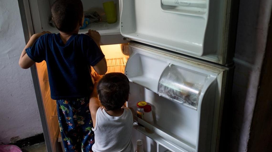Two children look inside an empty refrigerator at their home in the Catia neighborhood on the outskirts of Caracas.