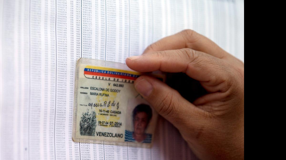 
An opposition voter checks for her name in the voting roster with her identification card at a poll station in Caracas, Venezuela, Sunday, May 17, 2015. Venezuelans are voting to select the opposition leaders who will run against the ruling socialist party’s candidates in upcoming legislative elections thought to be government critics’ first chance at an electoral victory in years.
