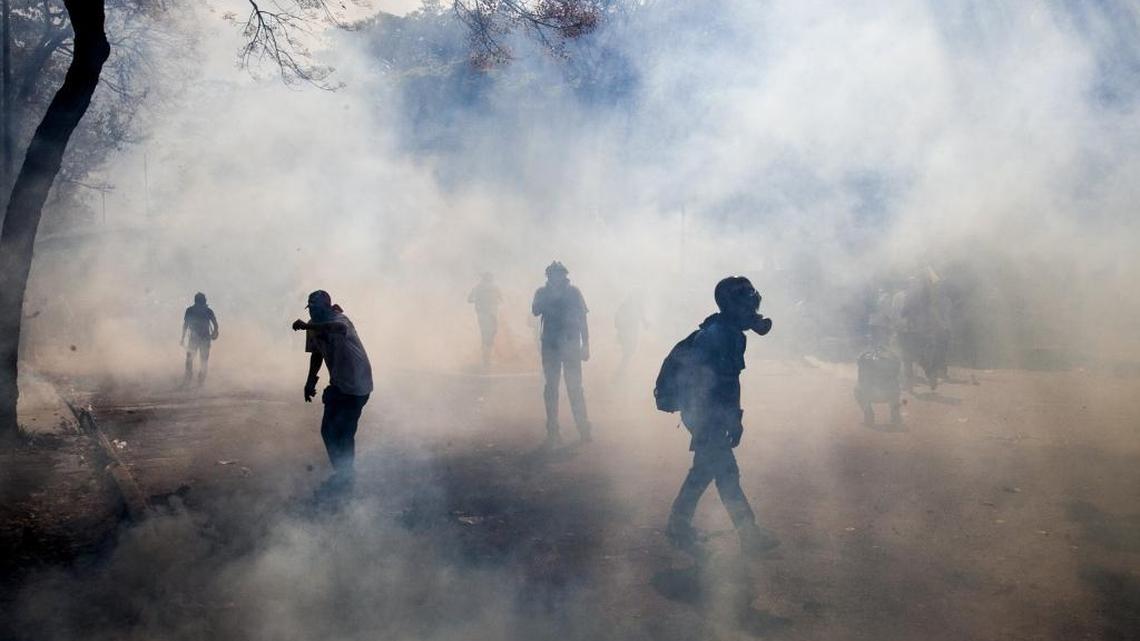 Demonstrators walk through a cloud of tear gas fired by the Bolivarian National Police during clashes in Caracas, Venezuela, Wednesday, March 12, 2014. A month of student-led demonstrations in a number of Venezuelan cities has left at least 25 people dead, according to the government. A new report by Human Rights Watch and Venezuela's PROVEA, released Monday, April 4, 2016, paints a picture of policing gone too far in Venezuela.