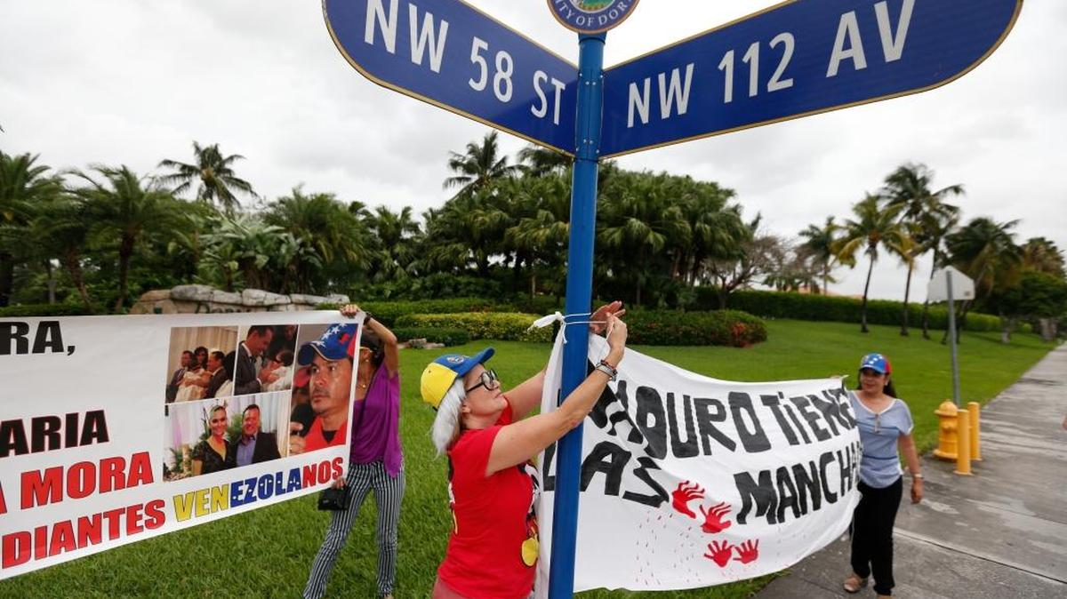 In this May 24 photo, demonstrators hang a banner outside a gated community where an alleged front man of prominent Chavista Gov. Gregorio Vielma Mora is believed to live with his beauty queen wife, in Doral, a Miami suburb.