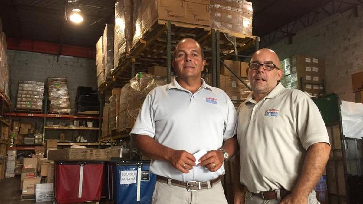 Rafael Landa (left) and Pedro Behrens, who run the Doral shipping firm Letterr Express, in front of medical shipments bound for families in Venezuela.