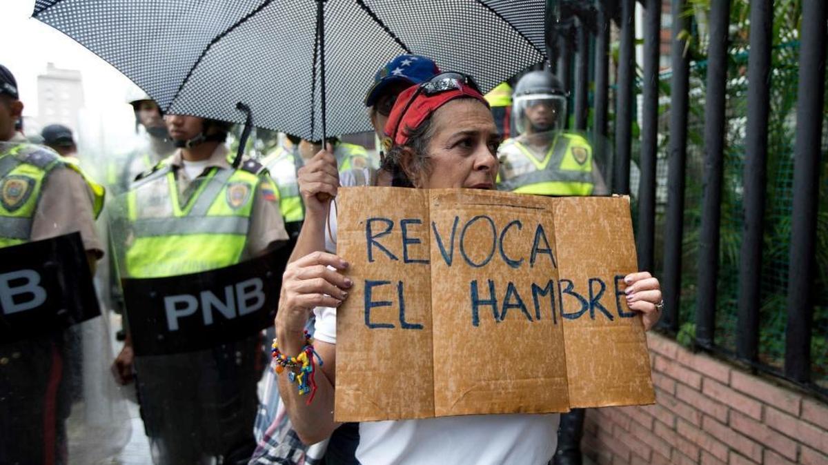 In this July 27, 2016, file photo, a woman holds a sign with a message that in reads in Spanish "Revoke hunger" during a protest march in Caracas, Venezuela. Venezuela's electoral authorites on Monday validated the signatures for a recall referendum process against President Nicolas Maduro.