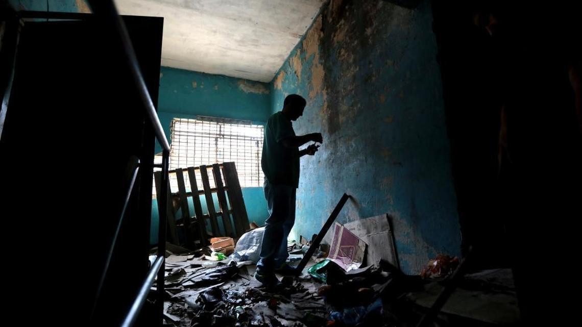 An employee of a grocery and liquor store cleans up the place after looters entered store during a protest last night in Caracas, Venezuela, Wednesday, April 12, 2017. Residents blocked some roads with debris and derelict furniture, burned garbage and banged pans to protest against Venezuela's President Nicolas Maduro.