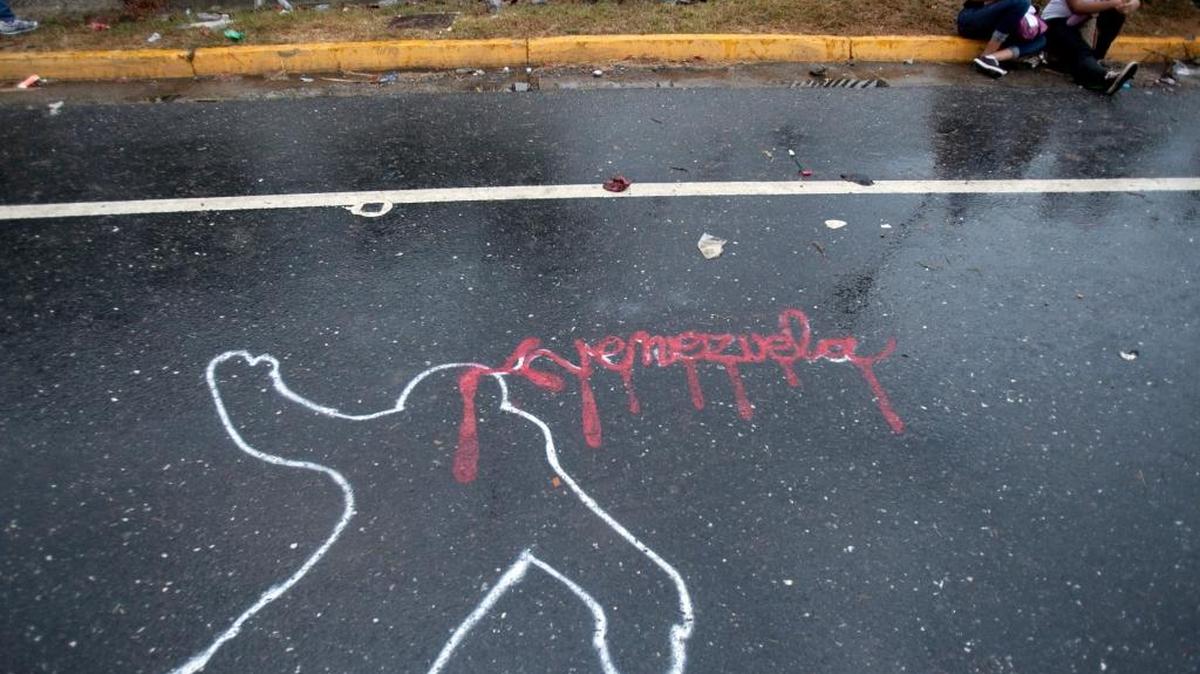 A Feb. 18, 2014, file photo in Caracas, Venezuela, shows a representation of a police chalk outline as part of an opposition protest, with the word Venezuela written in red to symbolize blood.