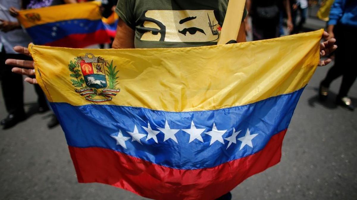 A government supporter wears a T-shirt featuring a stencil of late President Hugo Chavez's eyes and holds a national flag, during an anti-imperialist march to denounce Trump's talk of a "military option" for resolving the country's political crisis in Caracas, Venezuela, Monday, Aug. 14, 2017.