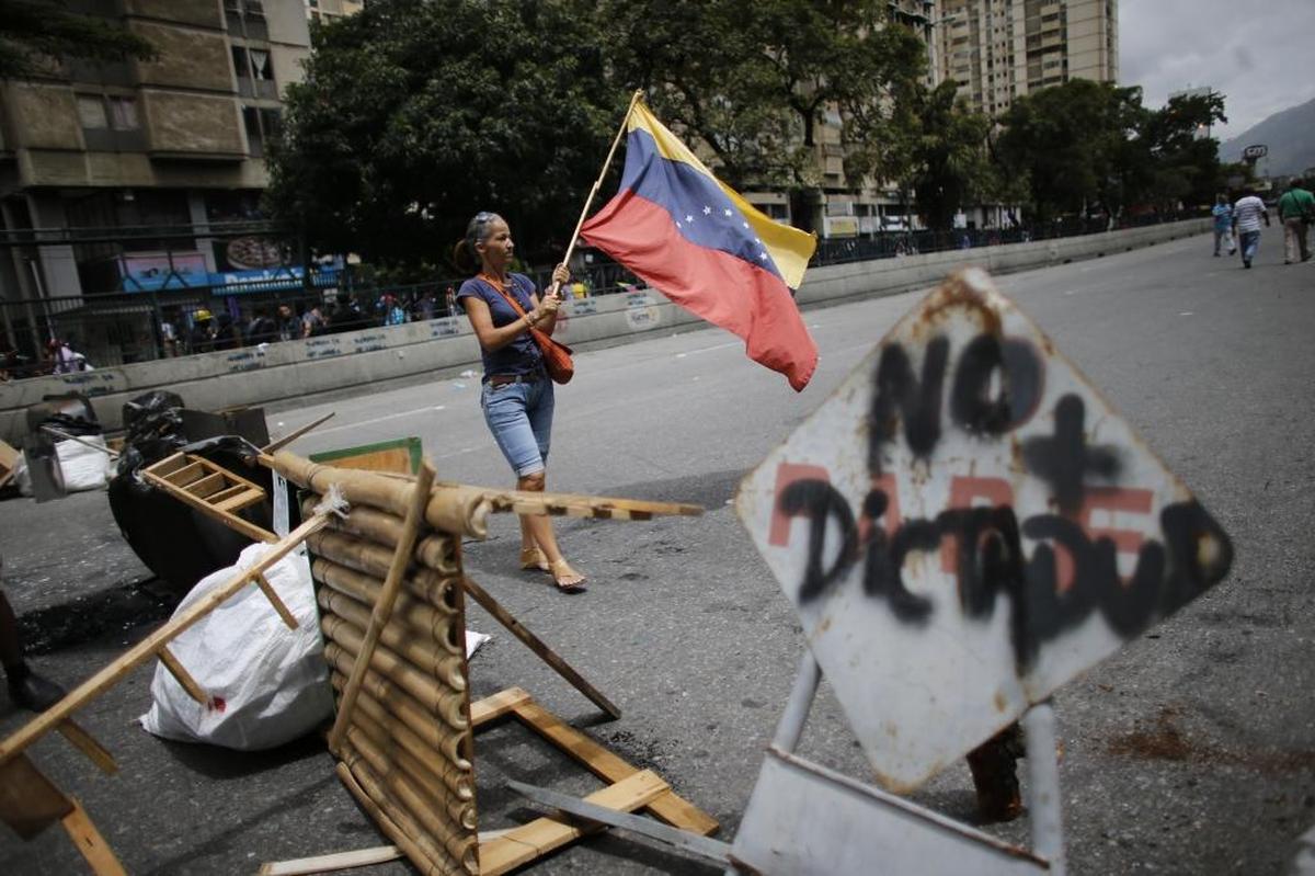 An anti-government protester waves a Venezuelan flag in the middle of the street during a call by the opposition to block roads for 10 hours in Caracas, Venezuela, Monday, July 10, 2017.