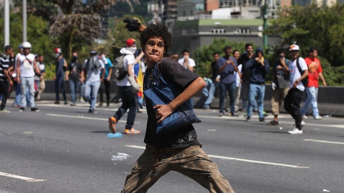 An anti-government demonstrator winds up to throw a stone at police, during the "taking of Caracas" march in on Thursday.