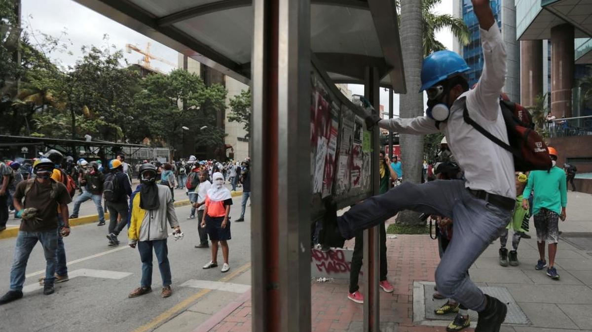 A demonstrator vandalizes a bus stop during anti-government protests in Caracas, Venezuela, Tuesday, May 30, 2017. Protests against President Nicolas Maduro's government have left dozens dead in the last two months.