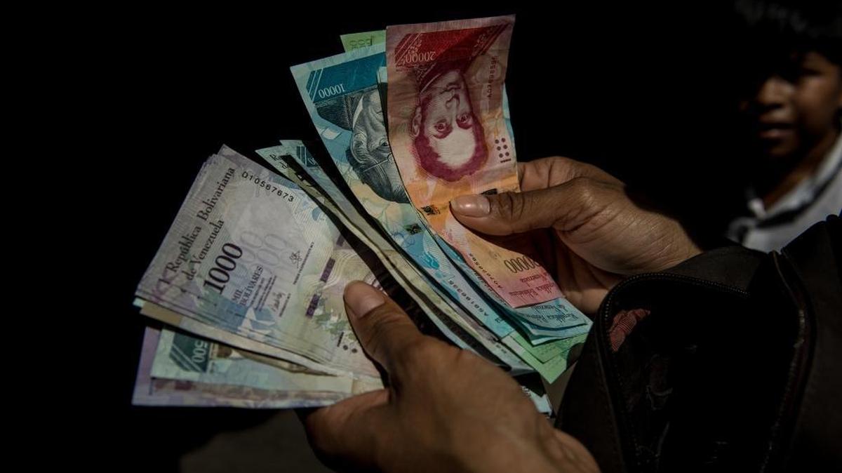 A shopper counting cash at an outdoor market in Caracas, Venezuela, Nov. 23, 2017. Venezuelans of all classes have been hit hard by sharply rising costs, and the economic turmoil has turned the most basic tasks — like food shopping and commuting — into feats of endurance.