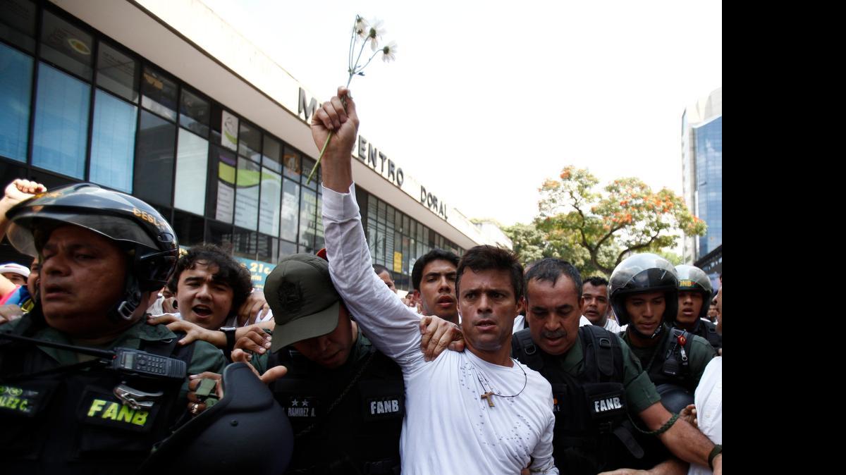 
In this Feb. 18, 2014 file photo, opposition leader Leopoldo Lopez, dressed in white and holding up a flower stem, is taken into custody by Bolivarian National Guards, in Caracas, Venezuela. Lopez has ended a 30-day hunger strike after authorities set a date for 2015 legislative elections. 
