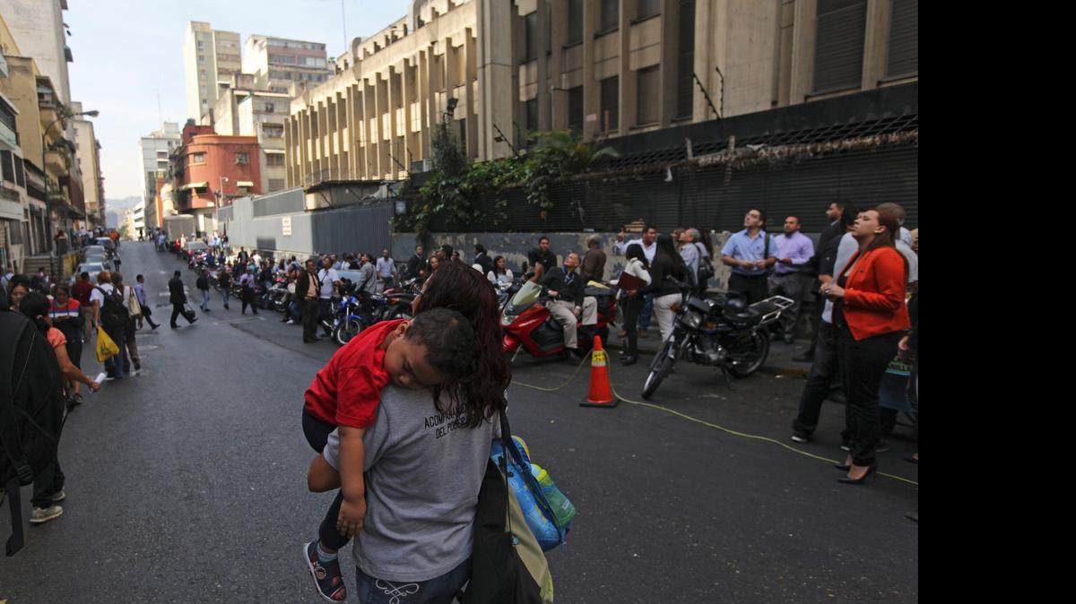 
Public employees stand outside their office buildings as they wait for power to be restored, in downtown Caracas, Venezuela, Tuesday, March 25, 2014. A forest fire cut electricity to most of Venezuela's capital and officials were still struggling to restore power to some areas Tuesday, 14 hours after the lights went out. 
