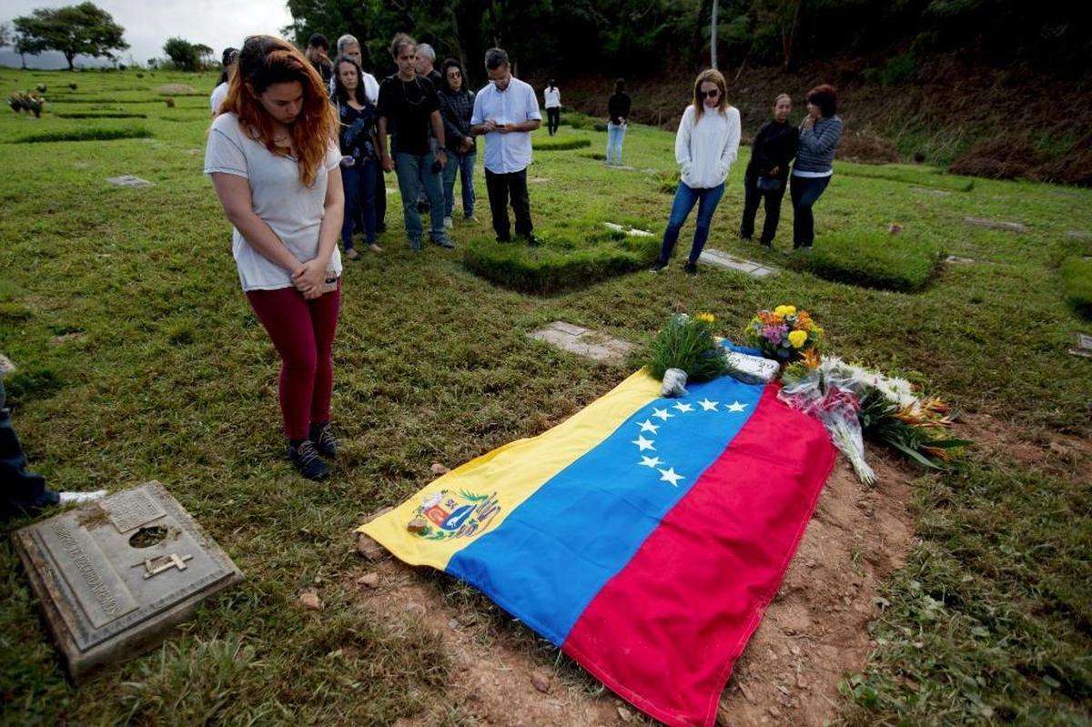Carolina Gil, a supporter of rebel policeman Óscar Pérez, mourns at the burial site covered with a Venezuelan flag at a cemetery in Caracas, Venezuela.