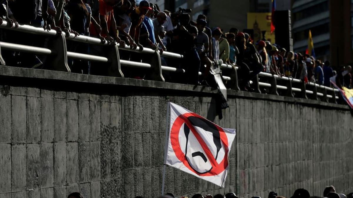 A demonstrator waves a flag with the crossed out image of Venezuela's President Nicolas Maduro during a tribute to those killed during protests, in Caracas, Venezuela, Monday, July 24, 2017. The opposition is staging daily protests days before President Maduro launches the rewriting of the country's constitution.