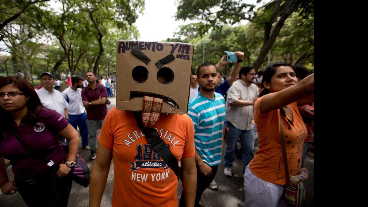 
A demonstrator wears a box on his head that reads in Spanish "Salary raise now" during a protest by public university professors and students as they prepare to leave the Central University of Venezuela (UCV) in Caracas, Venezuela, Thursday, May 28, 2015. Teachers are demanding salary raises while students demand improved bus transportation and that their schools' cafeterias and bathrooms be repaired. Students said their bathrooms and cafeterias are unusable due to lack of maintenance. Police blocked the protest from leaving the campus.
