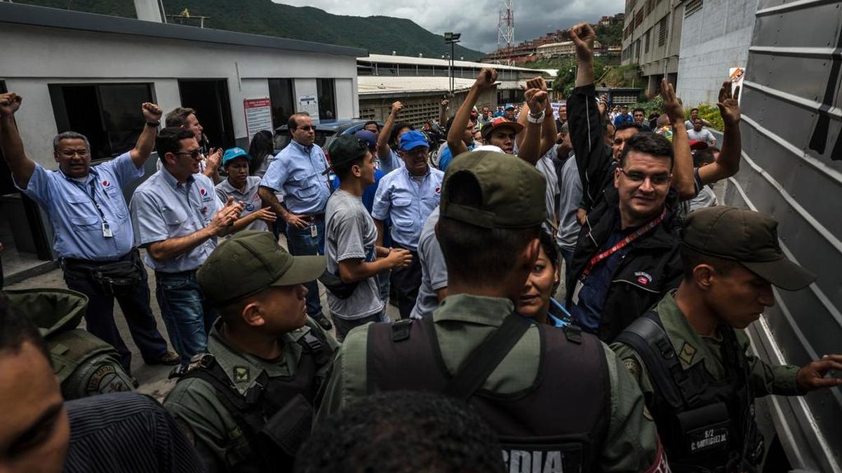 
Workers at a food distribution center, rear, react to Venezuelan soldiers, foreground, who took over the warehouse where they were working in Caracas, Venezuela, on Thursday, July 30, 2015. Soldiers seized a food distribution center rented by companies including Nestle SA, PepsiCo. Inc and Empresas Polar SA in Caracas as the government looks to boost support ahead of elections. The companies were given two months to remove equipment and stock at the La Yaguara industrial park, which will be converted to social housing, workers said. 
