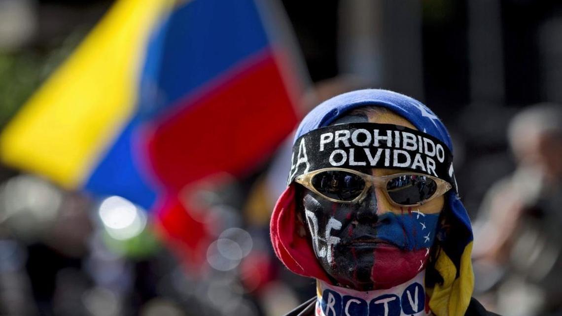 A demonstrator wears a banner that reads in Spanish: "Prohibited to forget" during a protest in Caracas, Venezuela, Sun., Feb. 12, 2017. Anti-government activists protested against President Nicolas Maduro's government on the third year anniversary of a student's killing by security forces that kicked off a wave of deadly unrest in 2014.