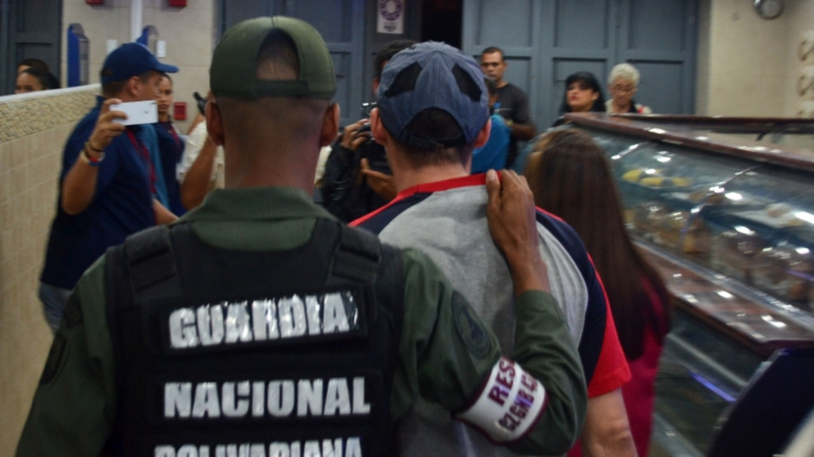 Venezuelan authorities escort an errant bread-maker out of a shop in Caracas. The government is cracking down on bakeries as it struggles with a bread shortage.