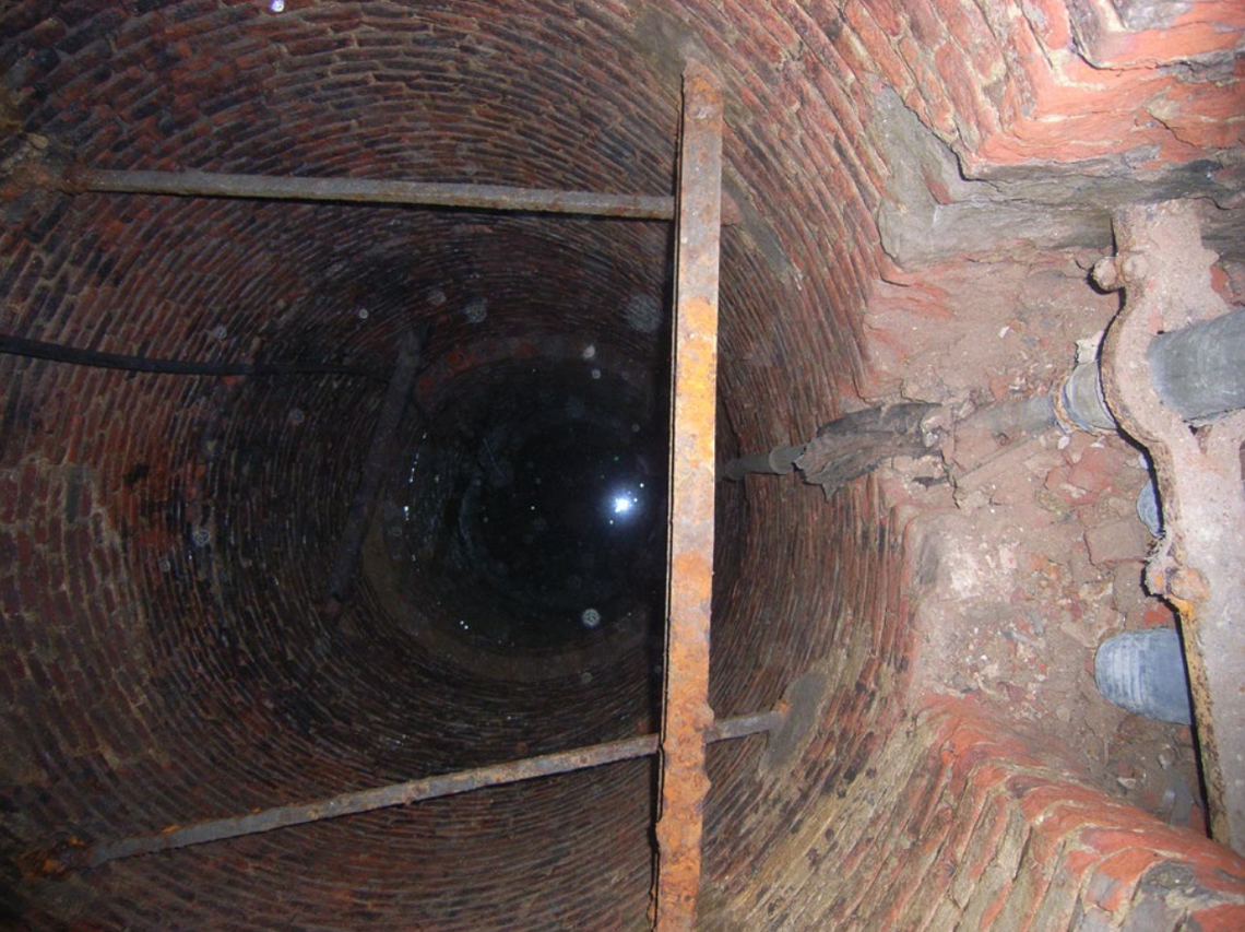 A view into the historic well with the base of the vertical shaft visible on the right.