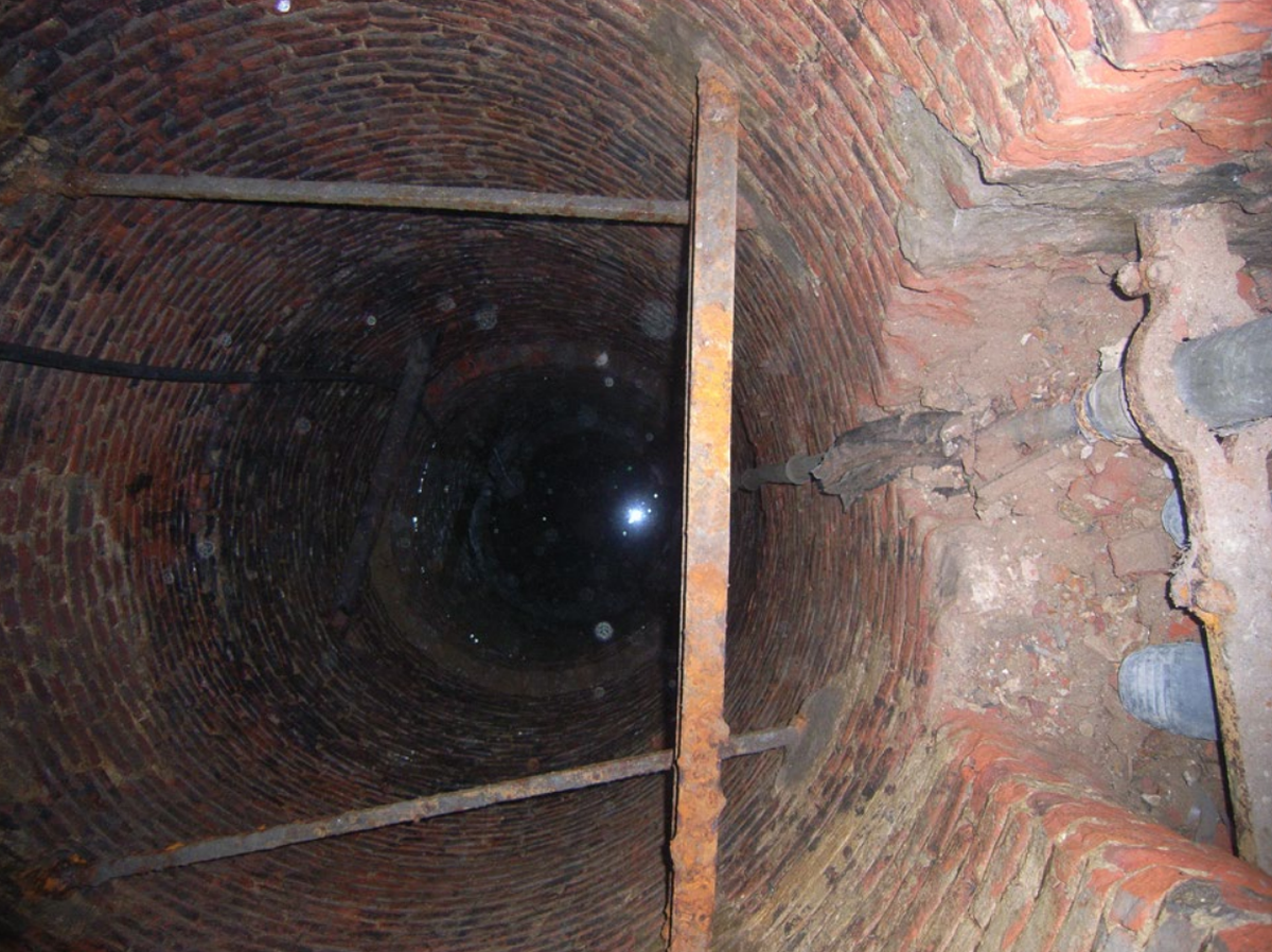 A view into the historic well with the base of the vertical shaft visible on the right.
