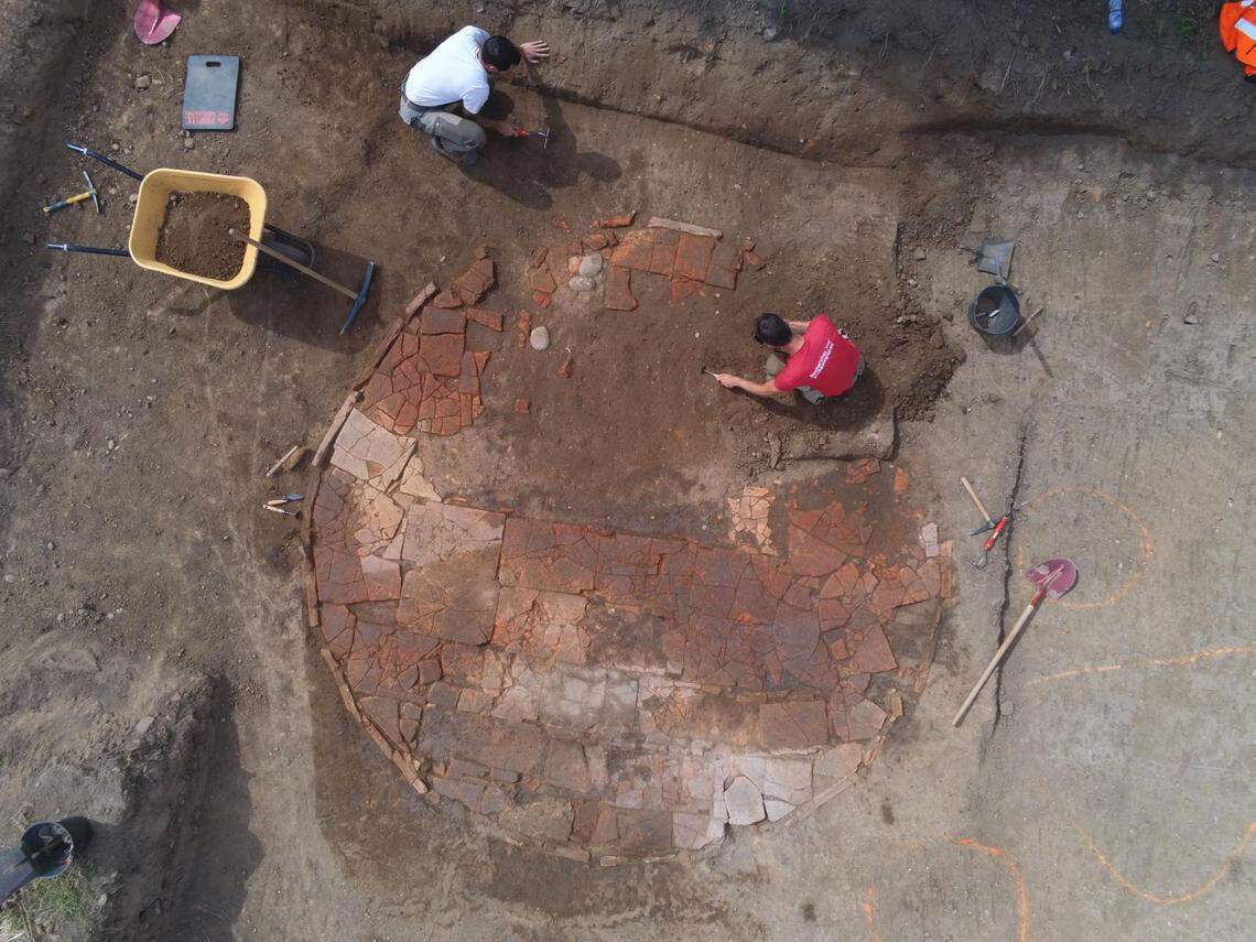 Archaeologists excavate an ancient tile wash basin.