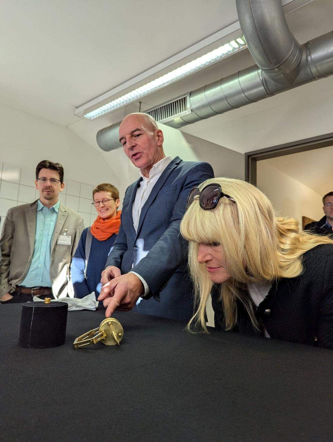 Officials look at the original ancient Roman lock (left) and a larger replica (right) displayed together.