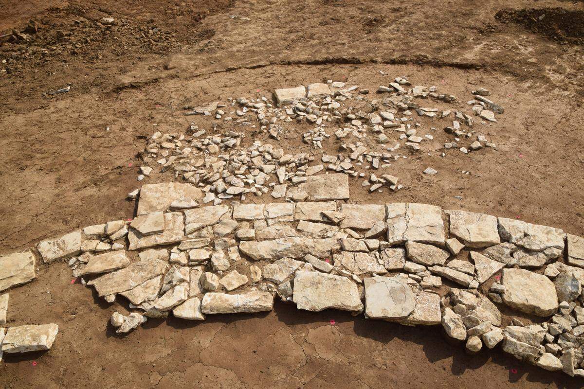 A close-up photo shows the square stone platform in front of the ancient Roman false tomb.