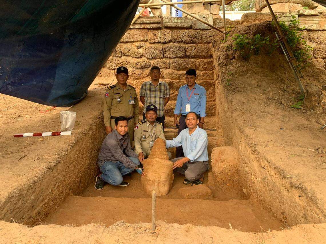 Archaeologists pose with the statue’s missing head.