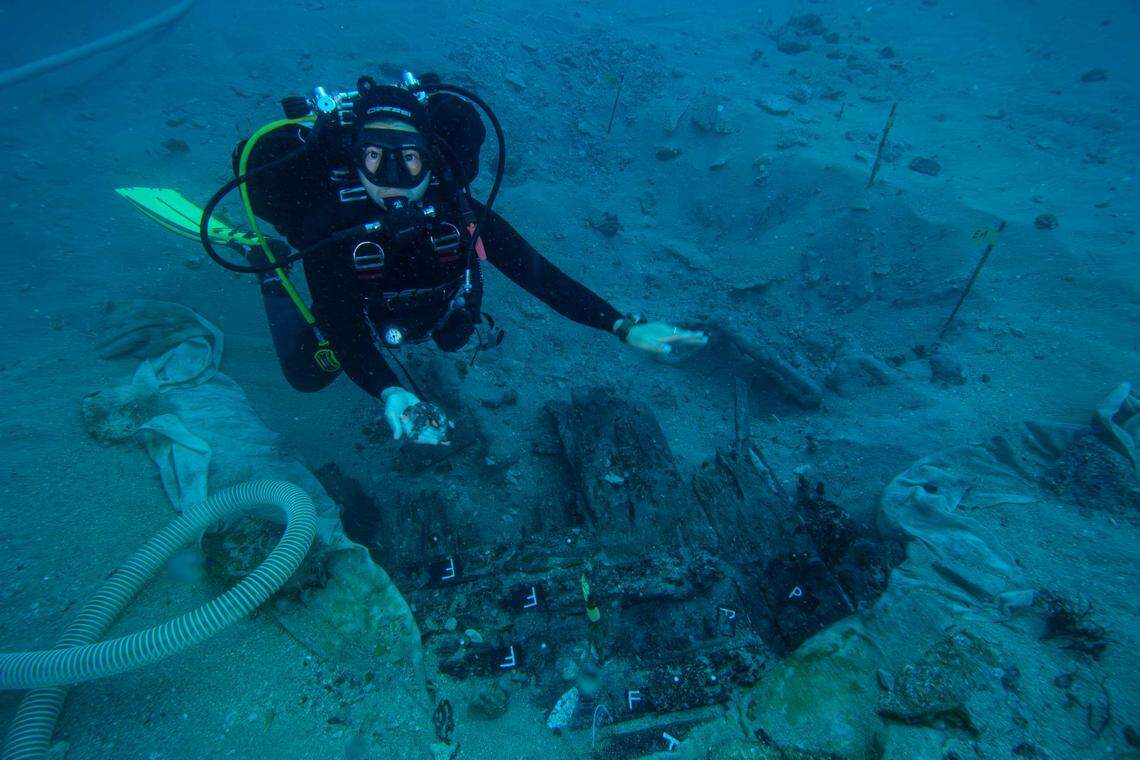 An archaeologist holds a fragment of a 400-year-old trumpet found at the wreck.