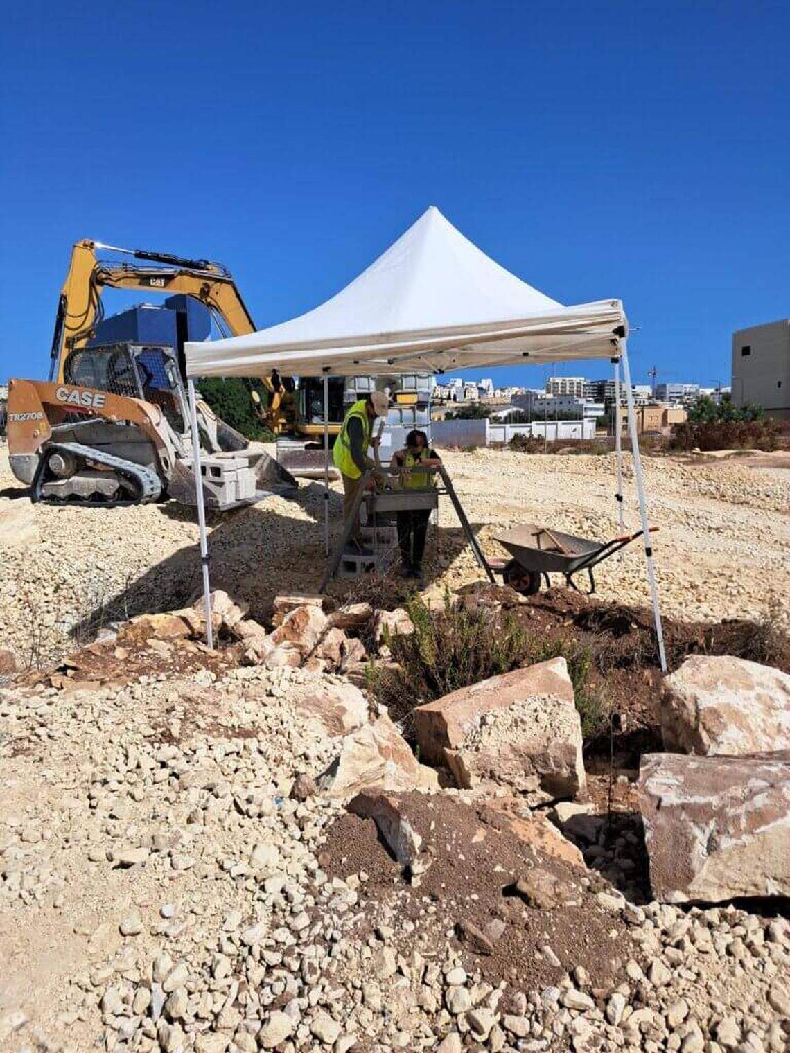 Excavations at the 2,300-year-old tomb with construction equipment visible in the background.