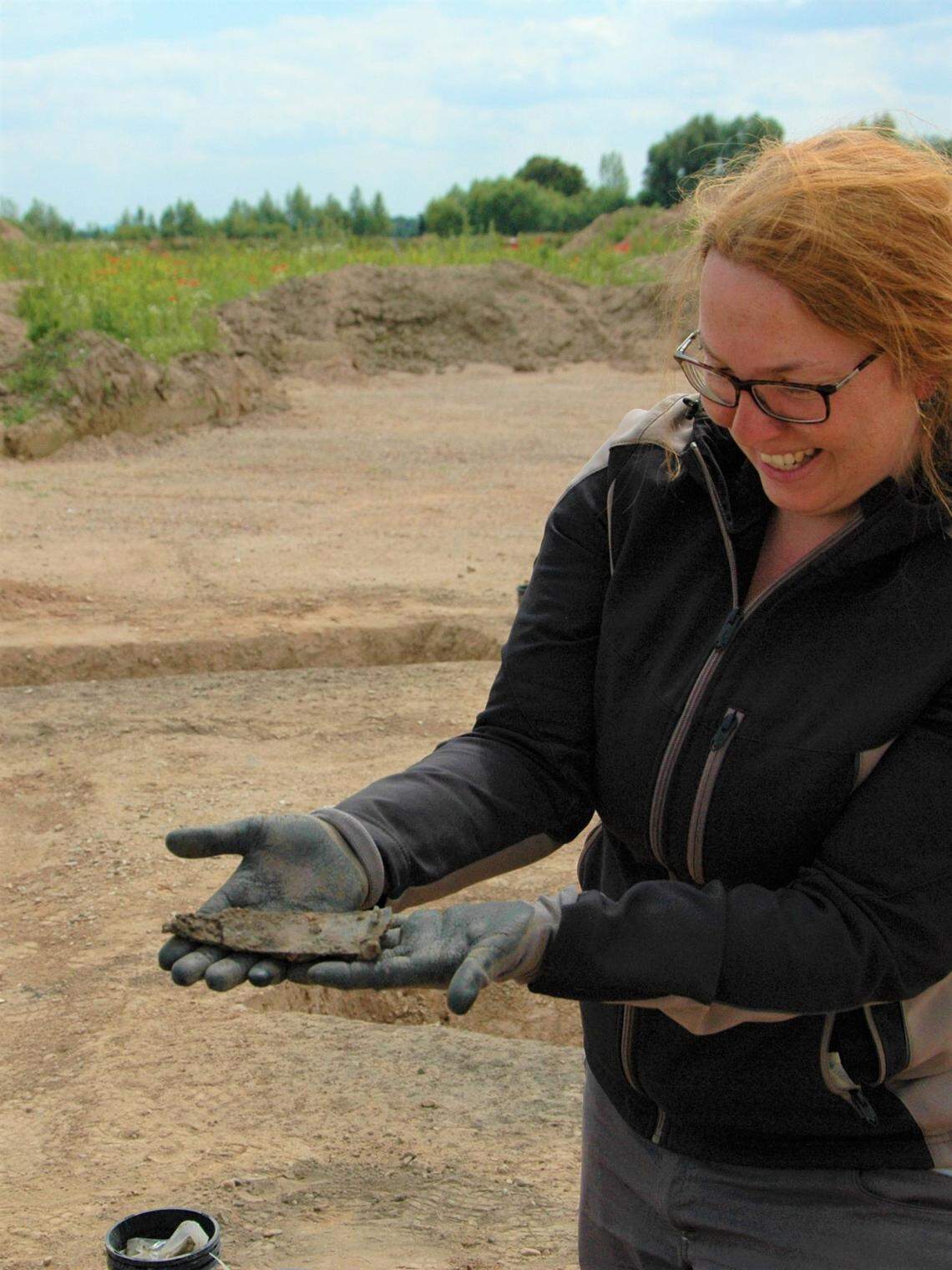 An archaeologist holds the ancient iron belt hook found at the site.