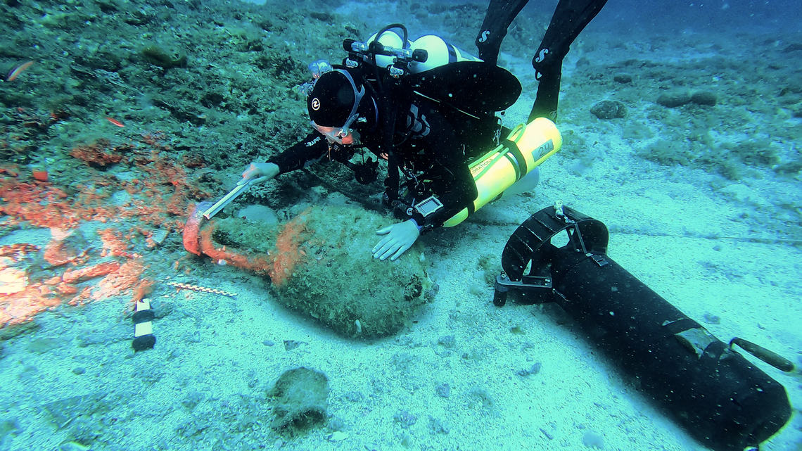 A marine archaeologist examines a large pottery vessel at the Antikythera wreck site.