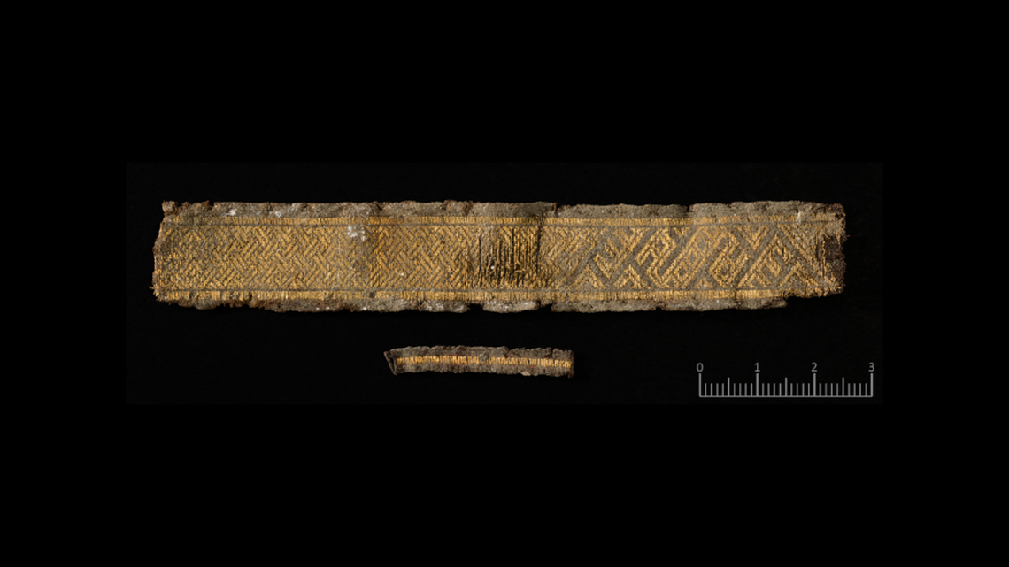 A woven gold band, likely part of a larger garment, found in the basement.