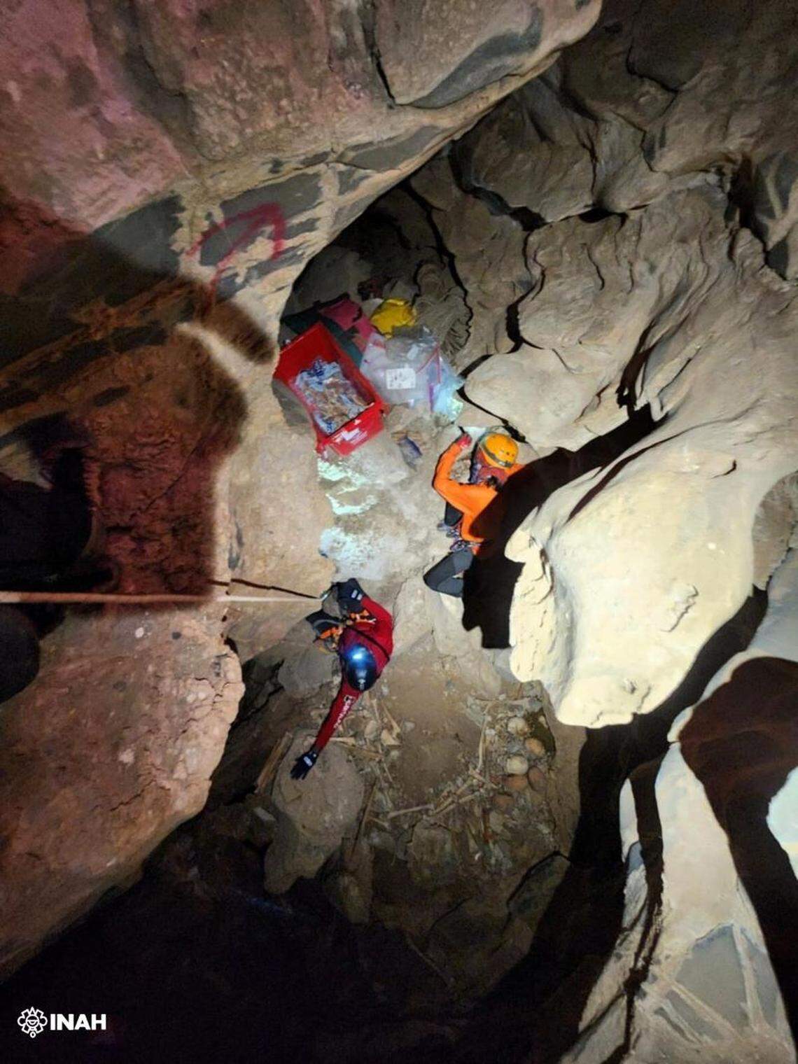 Cavers rappel into an underground chamber to reach the 500-year-old burials.